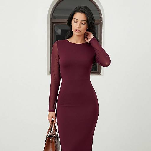 Photograph of a confident woman with dark hair, wearing a form-fitting, long-sleeve, burgundy dress, holding a brown handbag