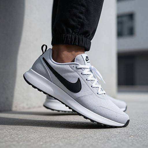 Close-up photograph of a person's feet wearing white Nike Air Max sneakers with black accents, black Nike logo, and black laces, standing on a