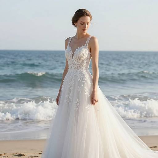 Photograph of a slender woman with fair skin and dark hair in an elegant white lace wedding dress standing on a sunlit beach with gentle waves in the