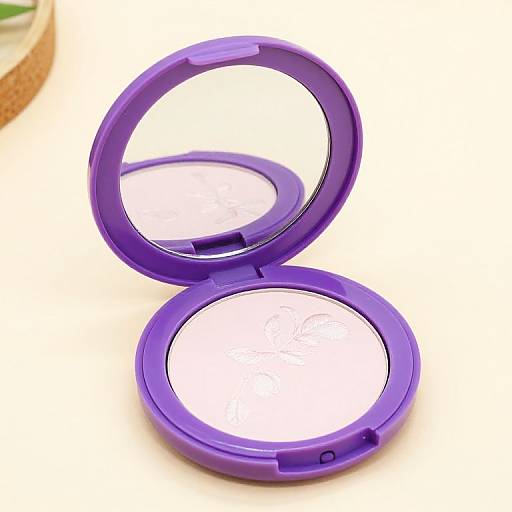 Photograph of an open, purple, circular compact mirror with a reflective surface, placed on a white background.