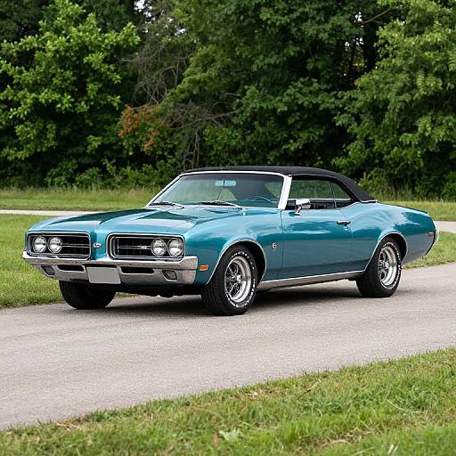 Photograph of a classic, bright blue, 1960s convertible Mustang with black soft top, parked on a gravel road in a lush, green