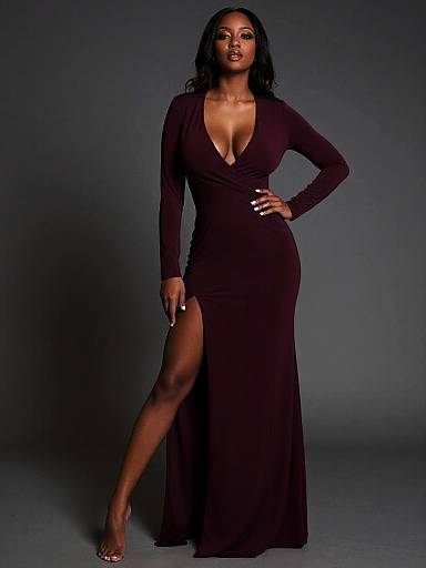 Photograph of a confident Black woman with long wavy hair, wearing a deep V-neck, long-sleeve, black gown with a high thigh
