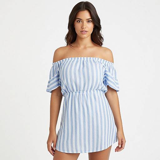 Photograph of a young woman with medium-length dark hair, wearing an off-the-shoulder, blue and white striped mini dress, standing against a
