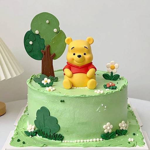 Photograph of a green-frosted cake with Winnie the Pooh wearing a red scarf, tree, flowers, and grass decorations.