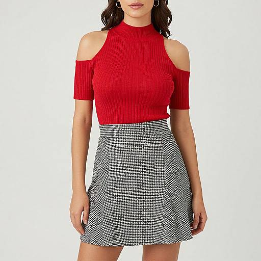 Photograph of a woman in a red, ribbed, off-shoulder top and black-and-white checkered skirt, standing against a plain white