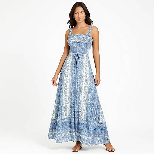 Photograph of a dark-haired woman in a shimmering, light blue, sleeveless maxi dress with a square neckline and bow tie, standing against a