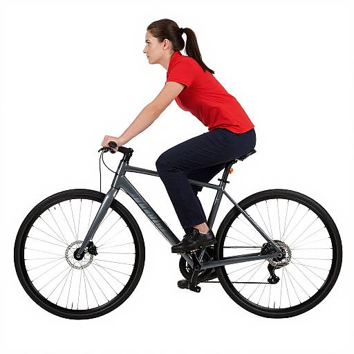 Photograph of a woman with brown hair in a ponytail, wearing a red shirt and black pants, riding a black mountain bike against a white background
