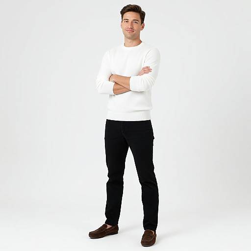 Photograph of a young, light-skinned man with short dark hair, standing with crossed arms, wearing a white shirt, black pants, and brown