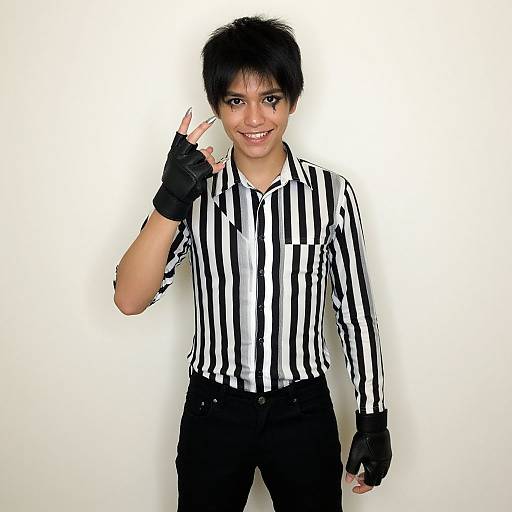 Photograph of a smiling young woman with short black hair, wearing a black and white striped shirt, black pants, and fingerless gloves, holding a