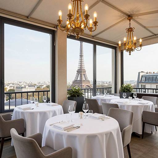 Photograph of an elegant Parisian restaurant with large windows showcasing the Eiffel Tower, white tablecloths, grey chairs, and ornate ch