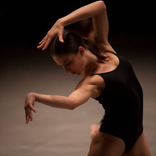 Photograph of a muscular woman in a black leotard, arms elegantly raised, dark background, focused expression, graceful pose, dim lighting.