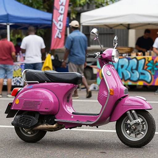 Photograph of a vibrant pink scooter with black seat, parked on a street, background includes people, blue and white tents, and colorful graffiti.