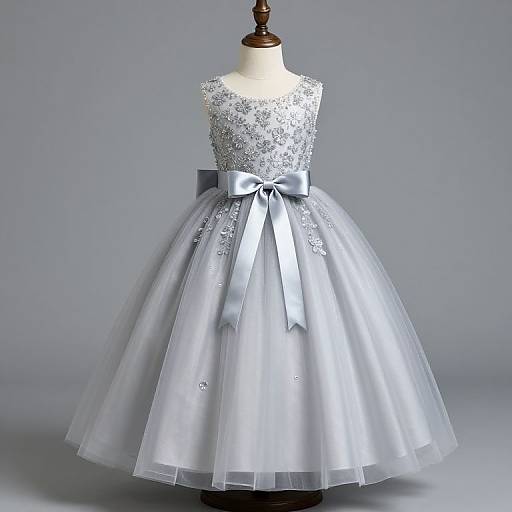 Photograph of a white, sleeveless, full-skirted wedding dress with silver sequin bodice, silver bow, and sheer tulle,