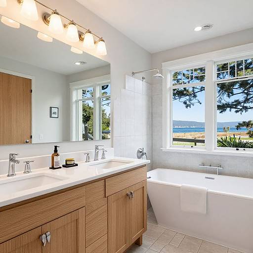 Bright, modern bathroom with wooden vanity, white sink, bathtub, large mirror, three light fixtures, window with ocean view, tiled floor.