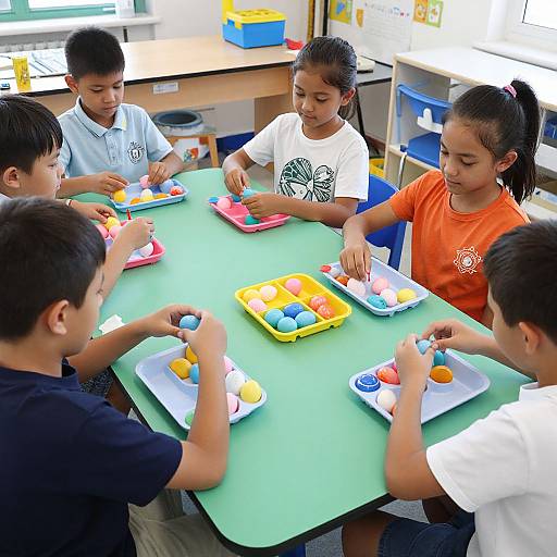 Photograph of five young Asian children, four boys and one girl, sitting around a green table in a classroom, playing with colorful plastic shape sorters