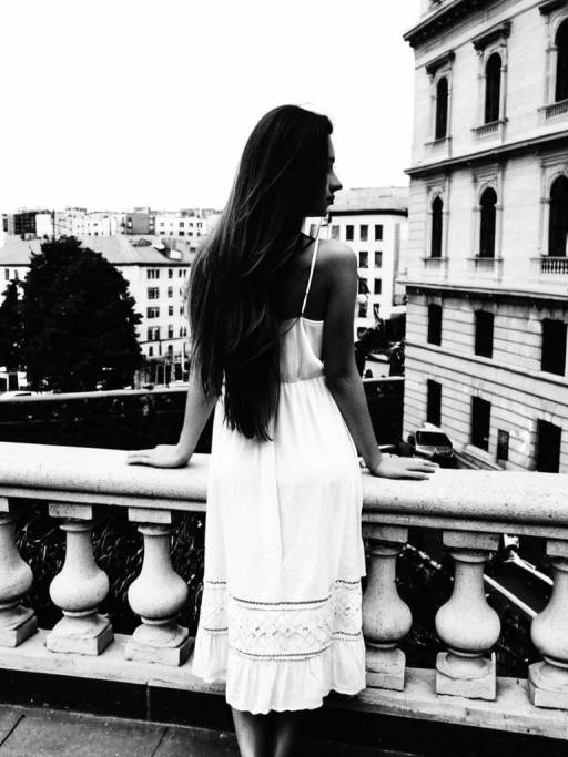Woman in White Dress on Urban Balcony