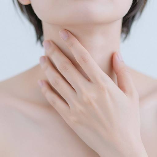 Close-up photograph of a light-skinned person's neck and hand gently touching it, with short black hair visible, against a white background.