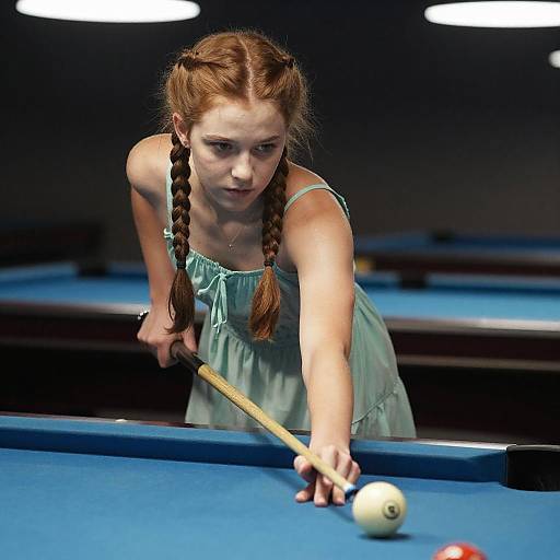 Photograph of a young woman with braided red hair, wearing a green dress, intensely aiming a pool cue at a white ball on a blue pool