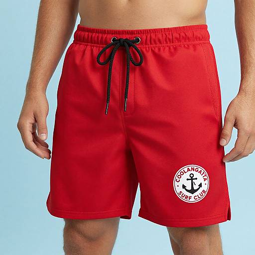 Photograph of a man's torso wearing bright red swim shorts with a black drawstring and white anchor logo, against a light blue background.