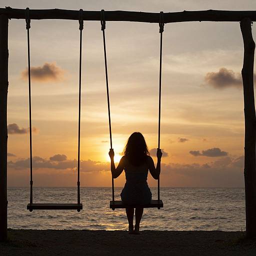 Silhouetted girl on swing at sunset, ocean background, golden sky, orange and pink hues, dark wooden frame, serene and nostalgic mood.