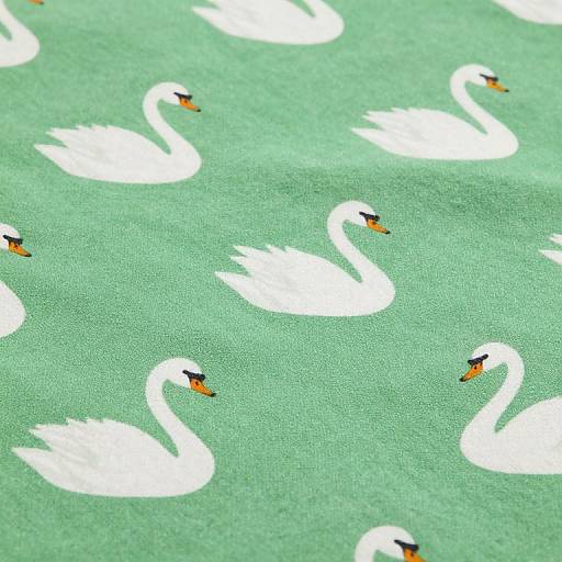 Photograph of a green fabric featuring a repetitive pattern of white swans with black and orange beaks, evenly spaced across the fabric's textured surface.