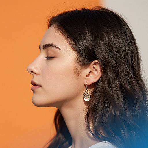 Photograph of a serene woman with closed eyes, dark wavy hair, and a gold circular earring, against an orange and white gradient background.