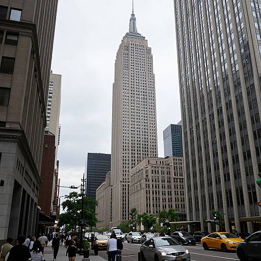 Photograph of a bustling urban street with towering skyscrapers, a prominent white spire building, yellow taxi, pedestrians, and gray buildings on both
