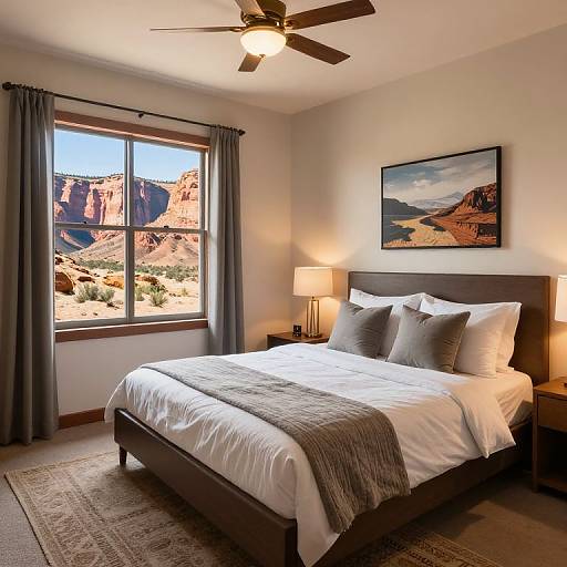 Photograph of a modern bedroom with a large window showcasing a desert landscape, dark wooden bed, white linens, gray pillows, gray blanket, bedside