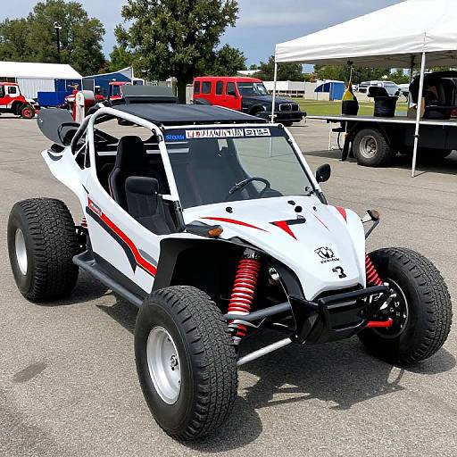 Photograph of a white, custom, off-road, open-wheel car with red accents, large black tires, and red springs, parked at a car