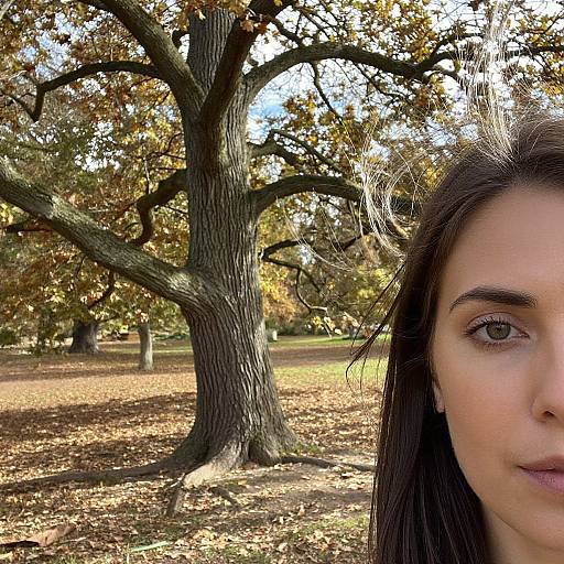 Photograph of a young woman with fair skin, dark brown hair, and brown eyes, partially visible on the right, standing in a park with a