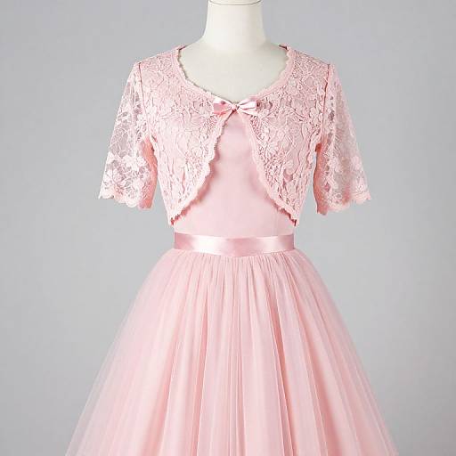 Photograph of a pink lace-cropped dress with a satin bow, flowing tulle skirt, displayed on a white mannequin against a light blue