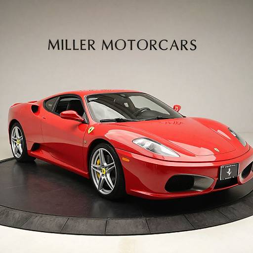 Photograph of a shiny red Miler Motorsports Ferrari, angled to the left, on a black circular platform against a plain white background. 