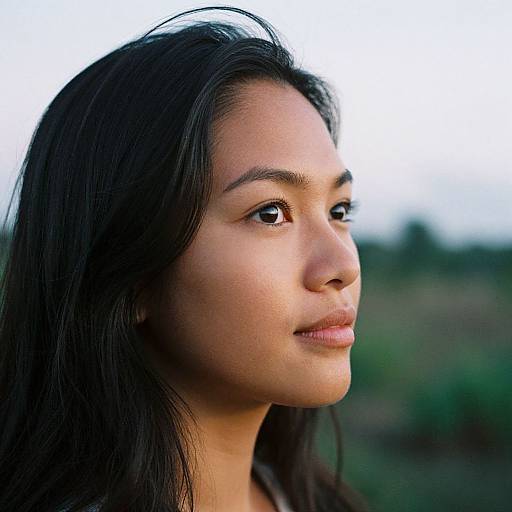Photograph of a young Asian woman with long, straight black hair, smooth brown skin, and brown eyes, gazing off to the right against a