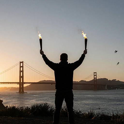 Silhouetted Person Holding Torches at Golden Gate Bridge Sunset
