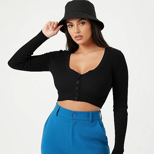 Photograph of a young woman with medium brown skin, long black hair, wearing a black bucket hat, ribbed black crop top, and bright blue