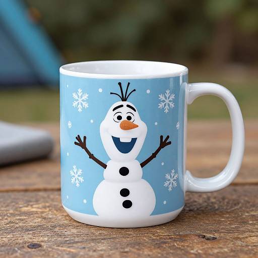 Photograph of a blue ceramic mug with a cartoon snowman design, featuring white snowflakes, on a wooden table.