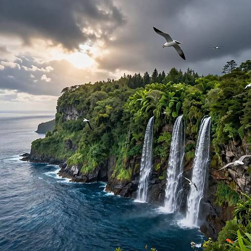 Photograph of lush, green cliffside with three cascading waterfalls, dramatic cloudy sky, sun peeking through, and a seagull in