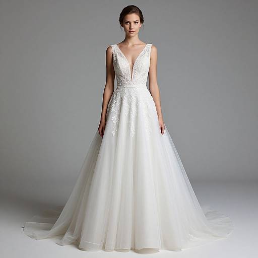 Photograph of a young woman with dark hair in an elegant, white, sleeveless wedding gown with a deep V-neck and lace bodice, standing