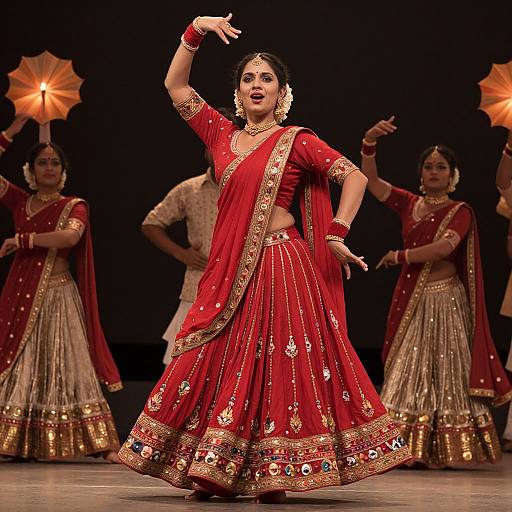 Photograph of an Indian classical dance performance: a woman in a red and gold traditional saree with intricate embroidery, adorned with jewelry, mid-dance