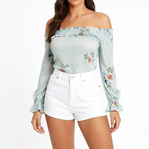Photograph of a woman with long brown hair, wearing an off-shoulder, floral-patterned light blue top and white high-waisted shorts