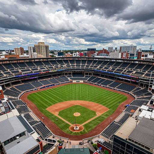 Aerial photograph of an empty, vibrant baseball stadium with green field, red dirt, and cloudy sky, surrounded by city buildings.