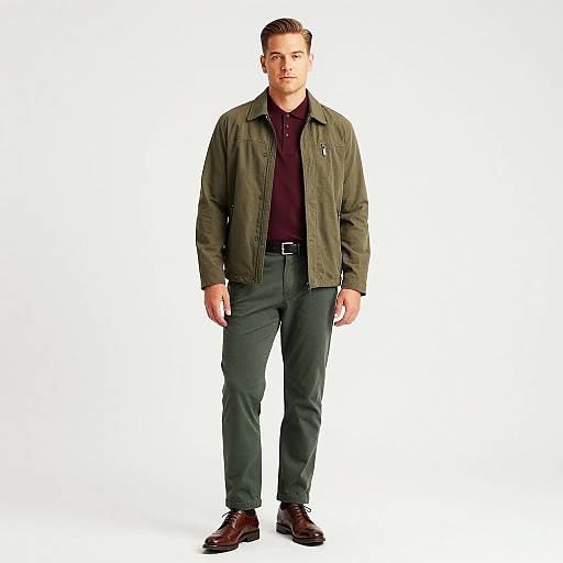 Photograph of a tall, light-skinned man with short brown hair, wearing an olive green jacket, dark maroon shirt, black pants, and