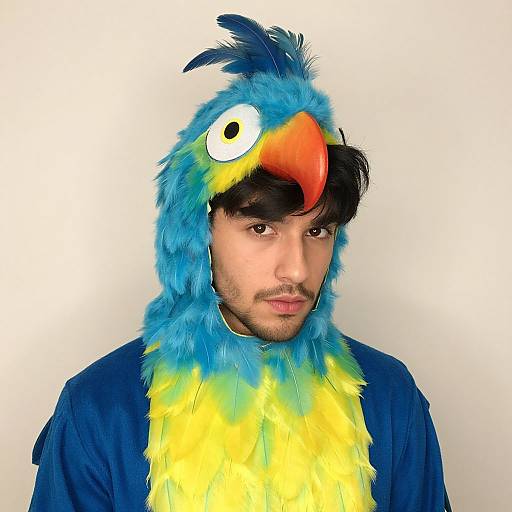 Photograph of a man with medium skin tone, dark hair, wearing a colorful bird costume with blue feathers, yellow chest, and a red beak