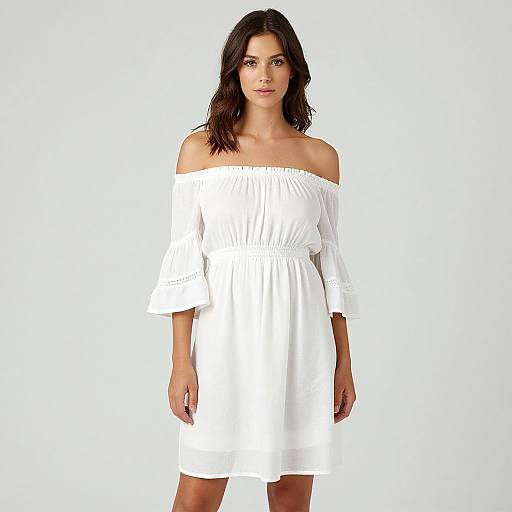 Photograph of a woman with medium brown skin and long dark hair, wearing an off-shoulder, white, knee-length dress against a plain white