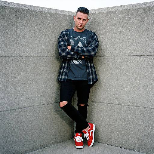 Photograph of a young, slim man with short black hair, wearing a plaid shirt, black graphic tee, ripped jeans, and red sneakers,