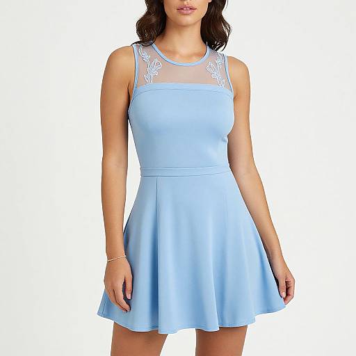 Photograph of a woman in a light blue, sleeveless dress with sheer lace shoulders, flared skirt, and a gold bracelet. White background.