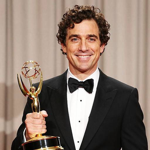 Smiling Man Holding Golden Emmy Award
