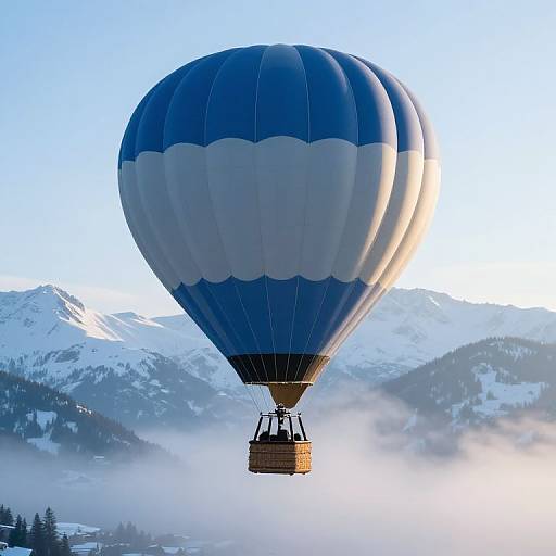Photograph of a blue and white hot air balloon with a wicker basket, soaring over snowy mountains and misty forest.