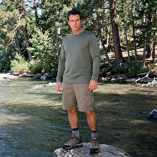 Photograph of a fit, fair-skinned man with short dark hair, wearing a green long-sleeve shirt, beige shorts, gray socks,