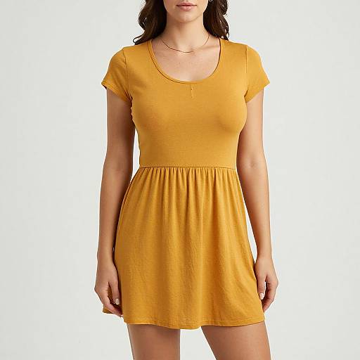 Photograph of a woman wearing a short-sleeved, mustard yellow dress with a round neckline and elastic waist, standing against a plain white background.